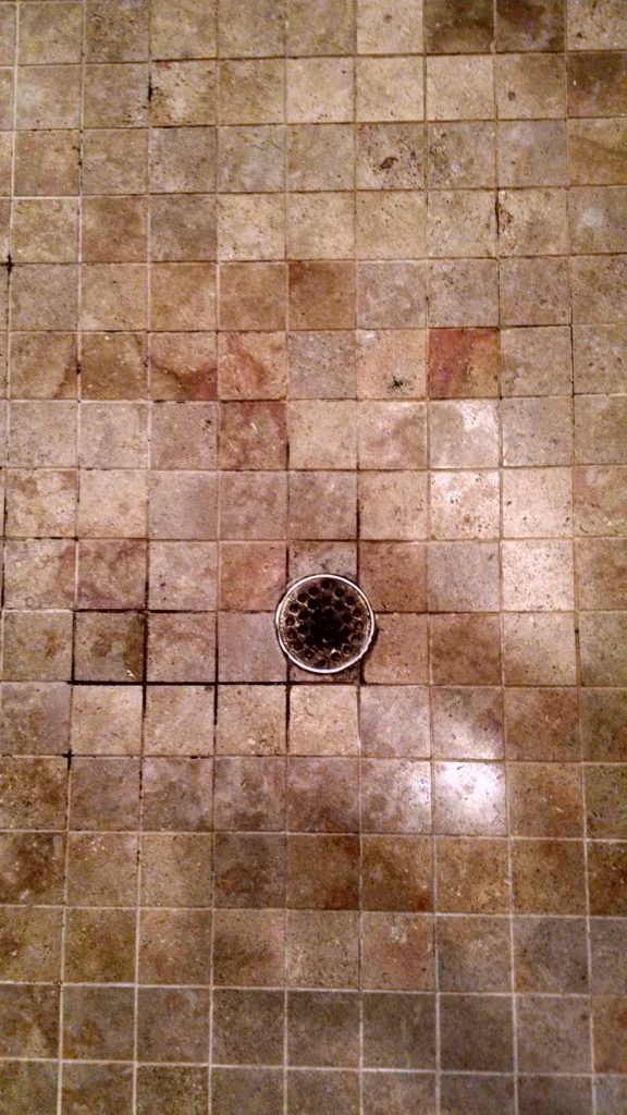 Travertine shower floor before restoration and grout replacement