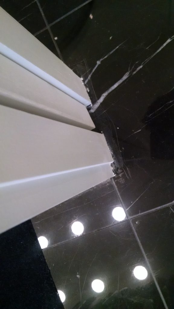 Deep scratches along edges of polished black marble flooring