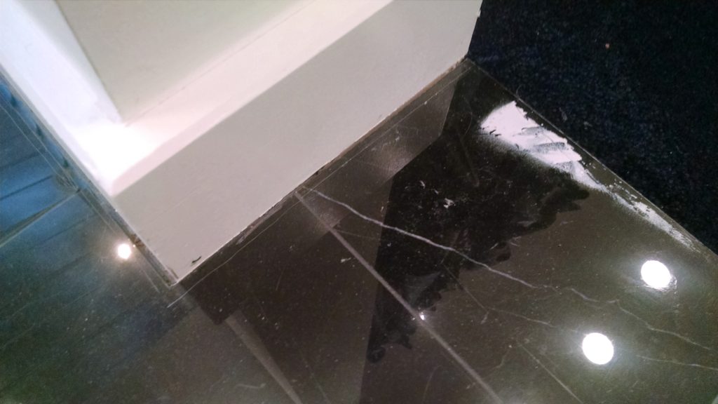 Scratches along edges of polished black marble flooring