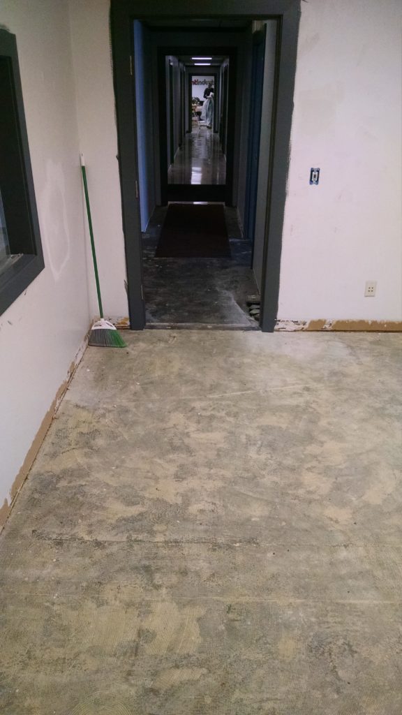 Concrete flooring with layers of carpet glue on it
