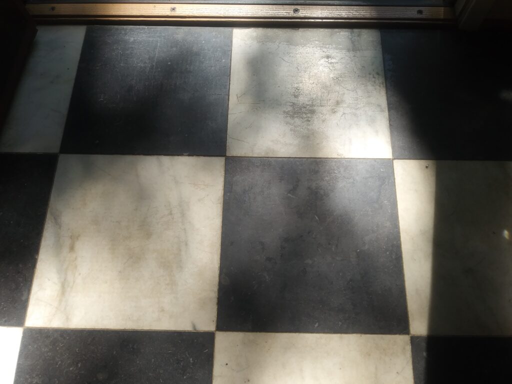 Extremely worn black and white checkerboard marble foyer flooring