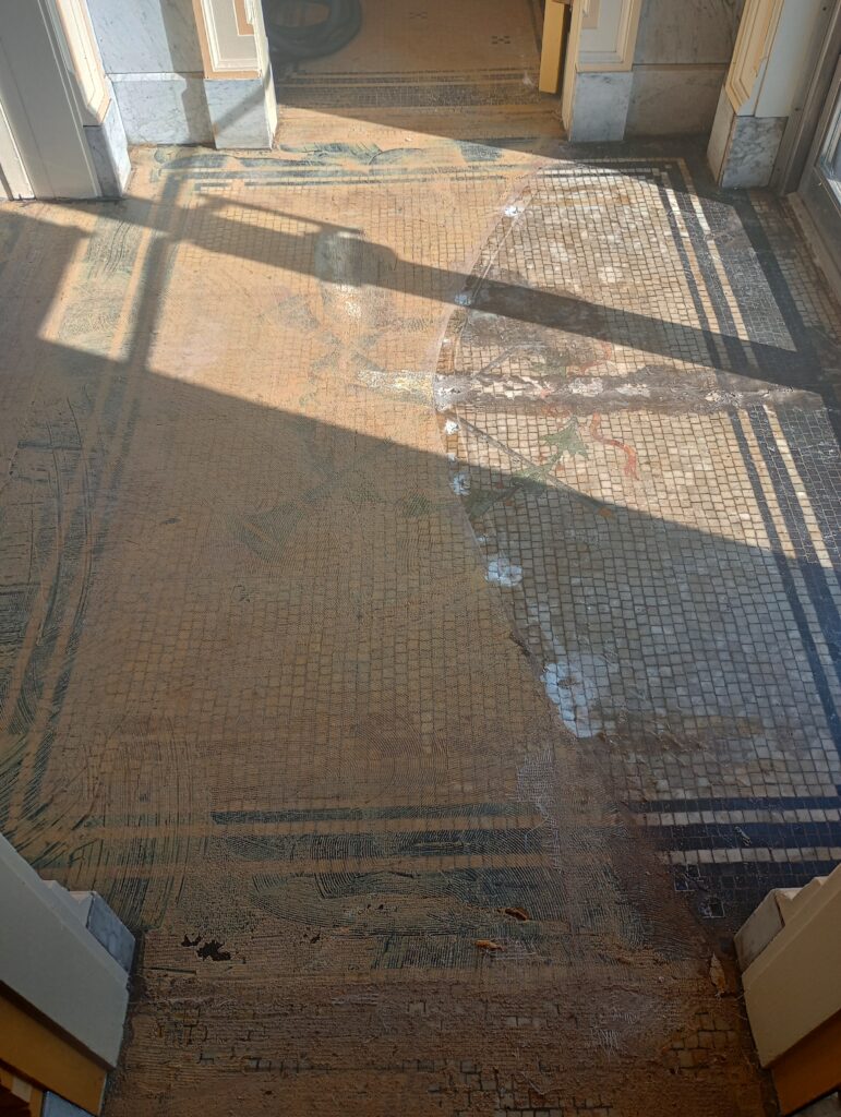 Marble mosaic tile flooring covered with layers of carpet glue and wax